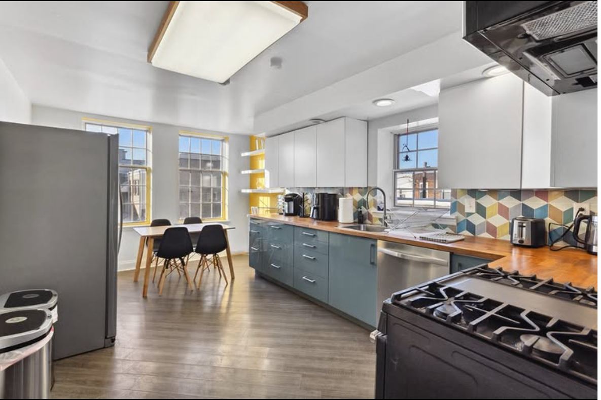 Bright kitchen with teal cabinets, wood counters, and a dining table by the windows