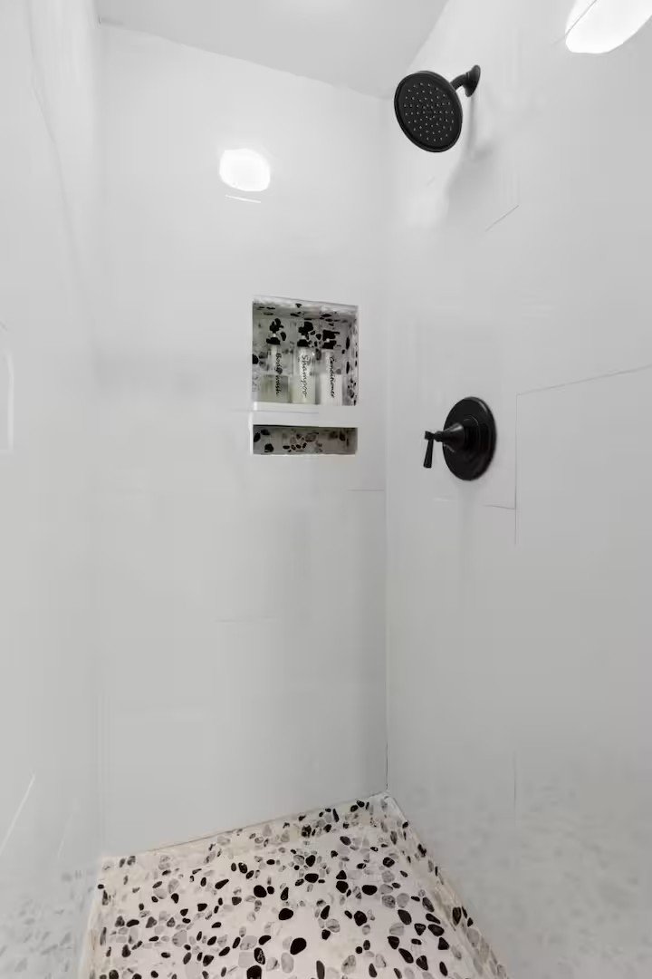 Walk-in shower with pebble mosaic floor and black fixtures