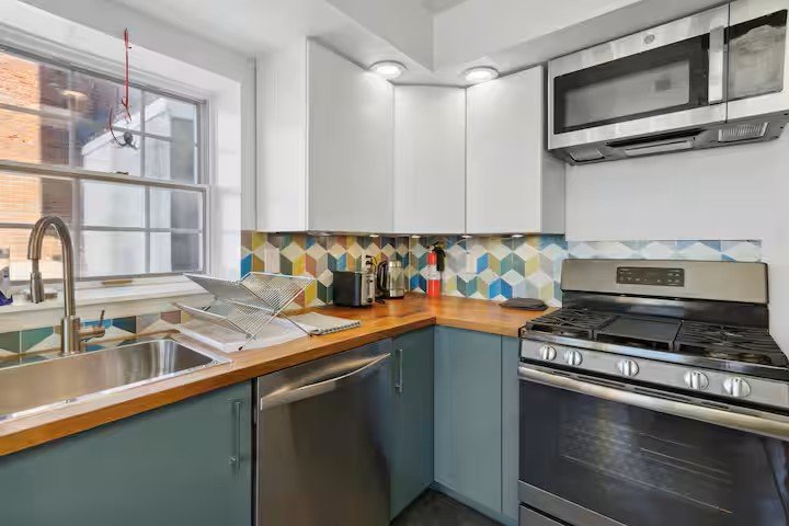 Kitchen with teal cabinets, wood counters, and geometric tile backsplash
