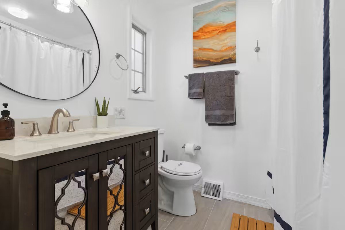 Master bathroom with dark vanity, round mirror, and shower curtain