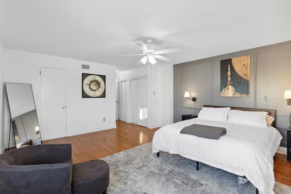 Master bedroom with grey paneled wall, rocket artwork, and seating