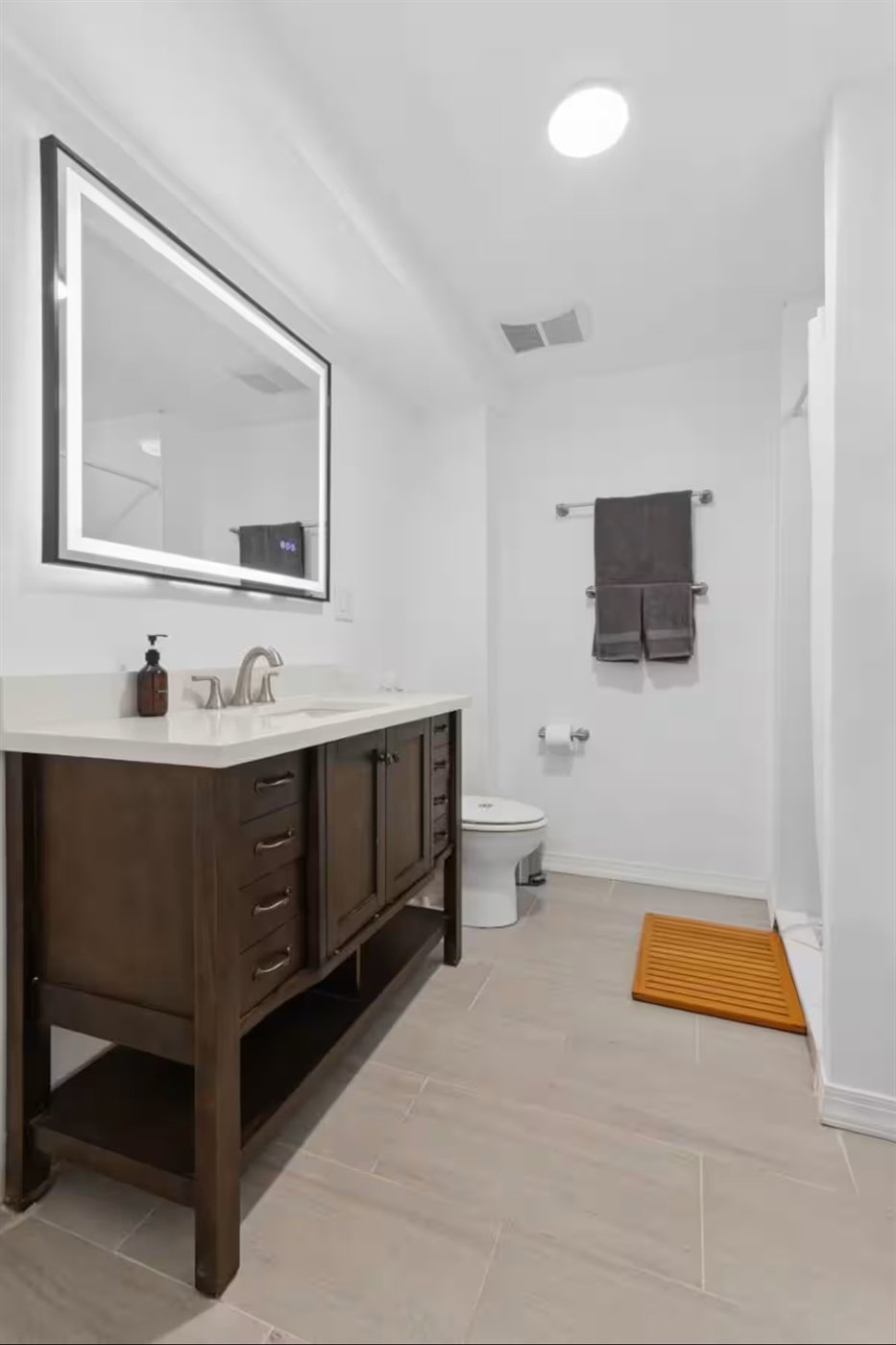 Second bathroom with dark vanity and an illuminated mirror
